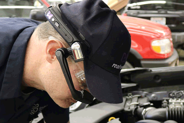 Ein Techniker benutzt eine Datenbrille bei der Fertigung eines KFZ-Motors.